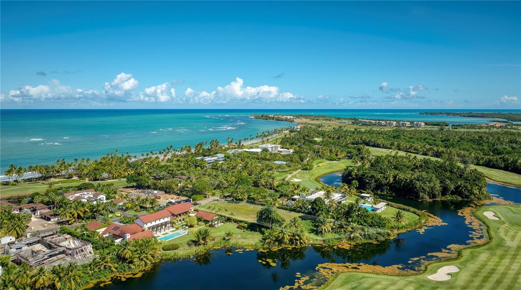 An aerial view shows a coastal resort with houses, a golf course, and a lake — 7000 BAHIA BEACH BOULEVARD UNIT 19 Las Estancias, RIO GRANDE, PR