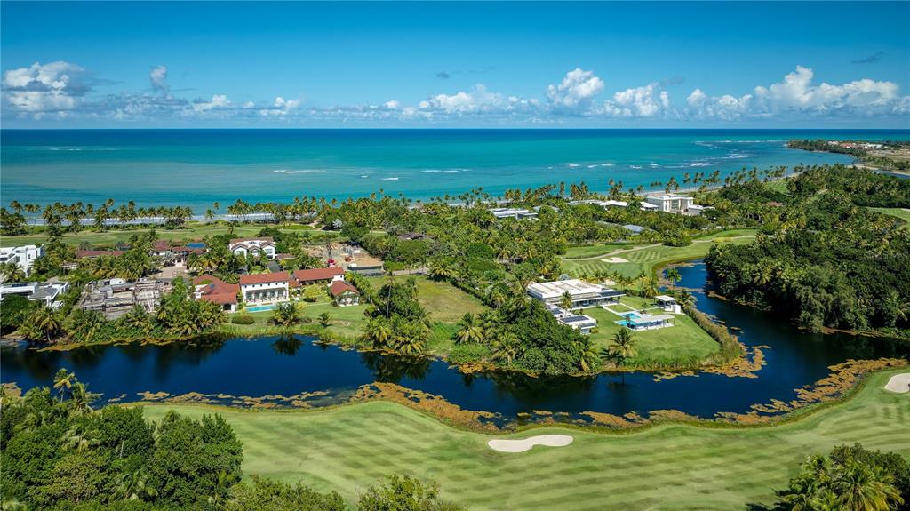An aerial view shows luxury homes situated along a golf course near the ocean — 7000 BAHIA BEACH BOULEVARD UNIT 19 Las Estancias, RIO GRANDE, PR