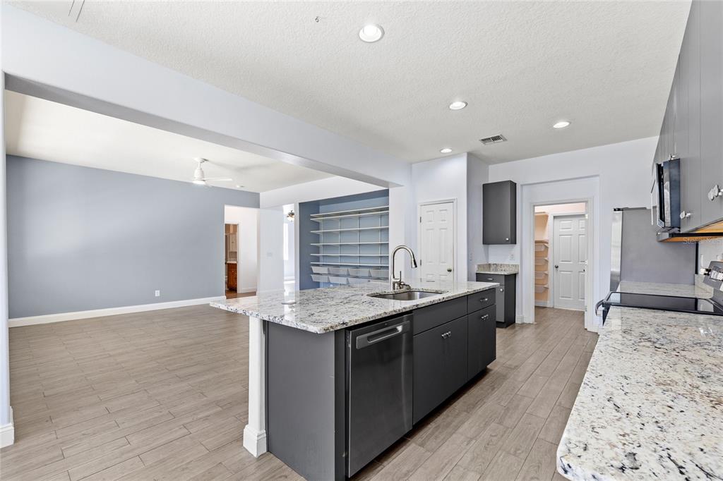 A kitchen with a granite-topped island, dark gray cabinets, and light wood-look tile flooring — 16943 SUNRISE VISTA DRIVE, CLERMONT, FL