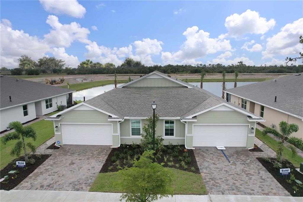 An aerial view shows a duplex home with two garages, paver driveways, and a pond — 44442 PALM FROND DRIVE, PUNTA GORDA, FL