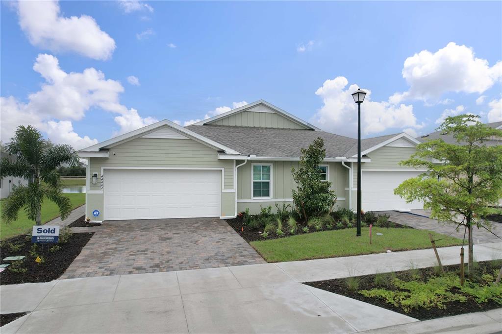 A light green single-story house with a two-car garage and a paved driveway — 44442 PALM FROND DRIVE, PUNTA GORDA, FL