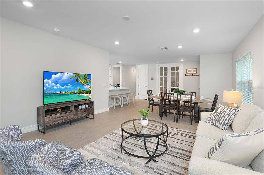A living room and dining area with light wood floors, neutral walls, and modern furniture — 44442 PALM FROND DRIVE, PUNTA GORDA, FL
