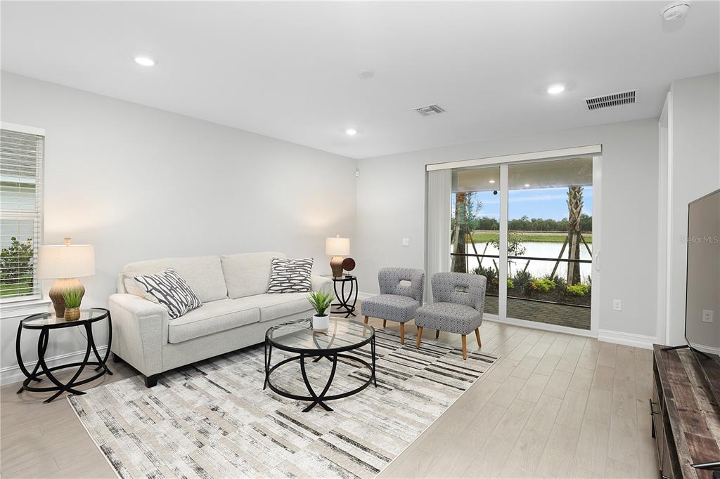 A living room features a light-colored sofa, two patterned chairs, and a sliding glass door — 44442 PALM FROND DRIVE, PUNTA GORDA, FL
