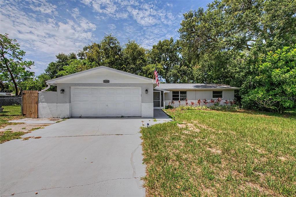 A single-story house with a white garage door, gray exterior, and a concrete driveway — 11592 110TH TERRACE, LARGO, FL