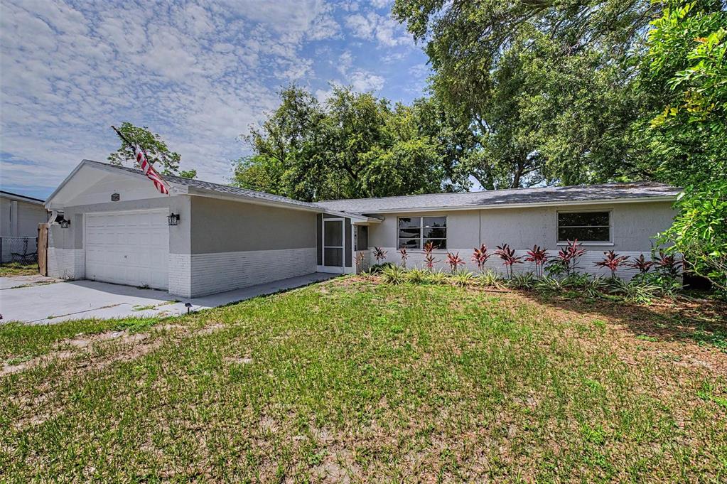 A single-story house with a white garage, gray exterior walls, and a front lawn — 11592 110TH TERRACE, LARGO, FL