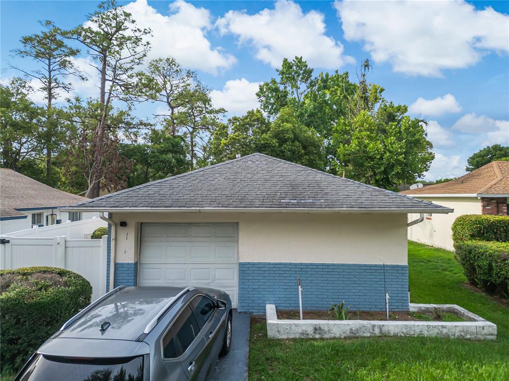 A detached garage with a gray shingled roof, blue brick base, and white stucco upper walls — 4721 WATCH HILL COURT, ORLANDO, FL
