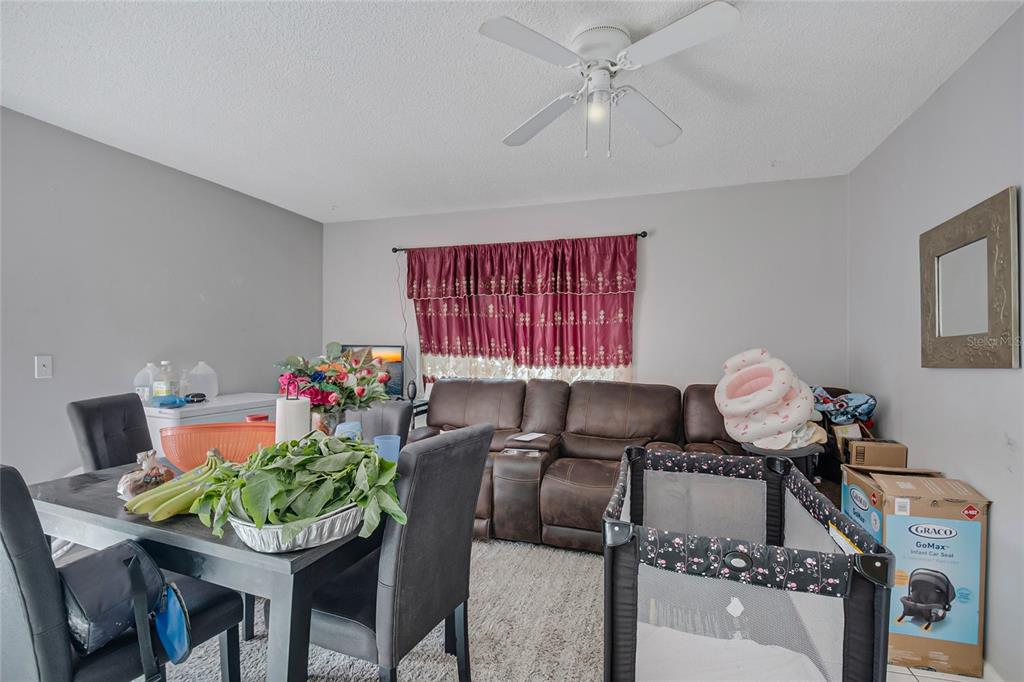 A dining area and living space feature a brown leather sofa, dining table, and playpen — 4721 WATCH HILL COURT, ORLANDO, FL