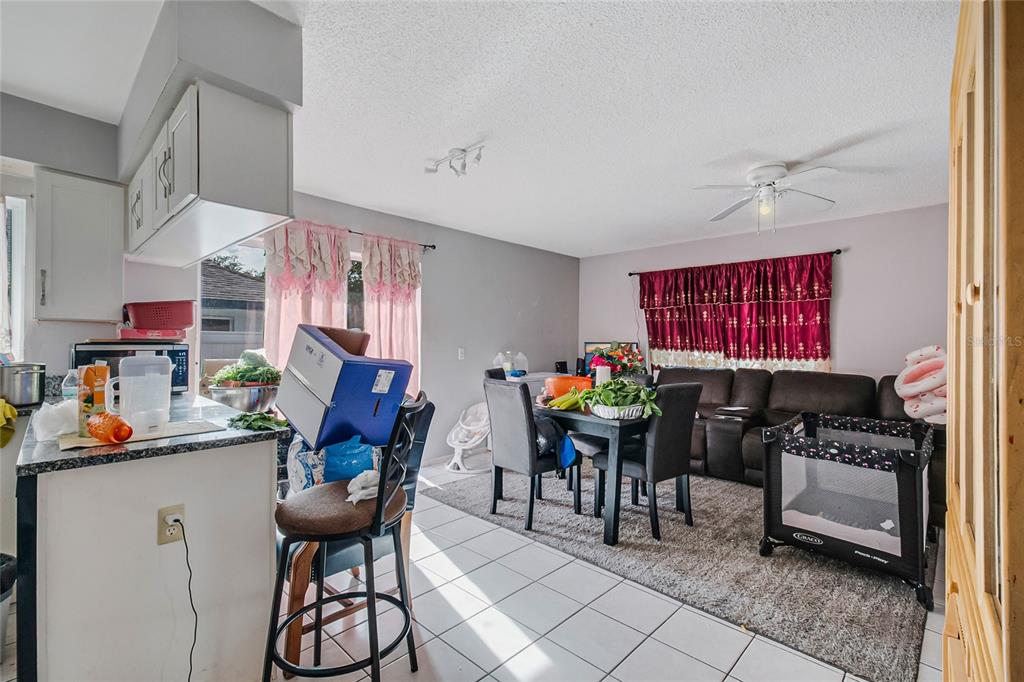 An open-concept kitchen and living area features tile flooring, a dining table, and a sofa — 4721 WATCH HILL COURT, ORLANDO, FL