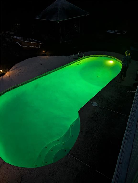 A two-story house at night with a glowing blue swimming pool and an illuminated deck — 6817 MITCHELL CIRCLE, TAMPA, FL