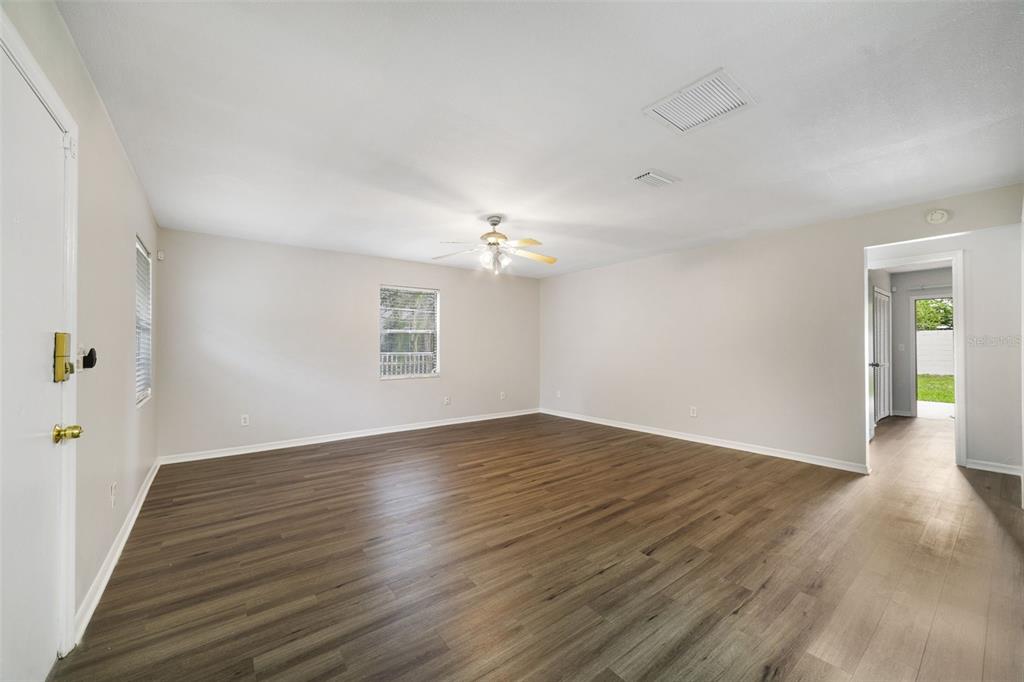 An empty living room features light-colored walls, wood-look flooring, and a ceiling fan — 5444 PEACO PLACE, WINTER PARK, FL