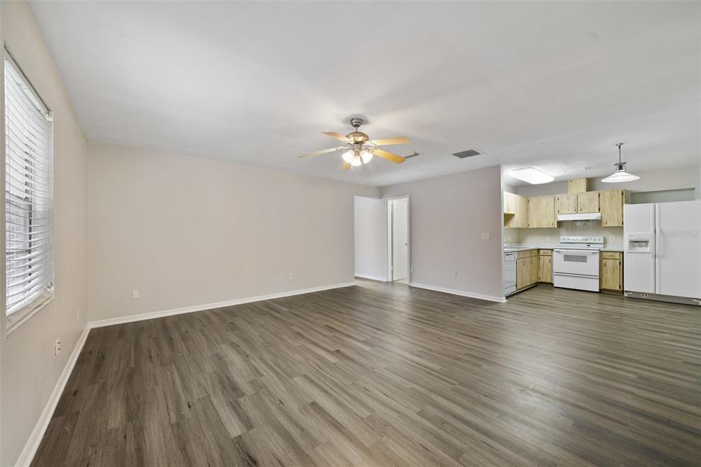 An open-concept living area with wood-look flooring, a ceiling fan, and an adjacent kitchen — 5444 PEACO PLACE, WINTER PARK, FL