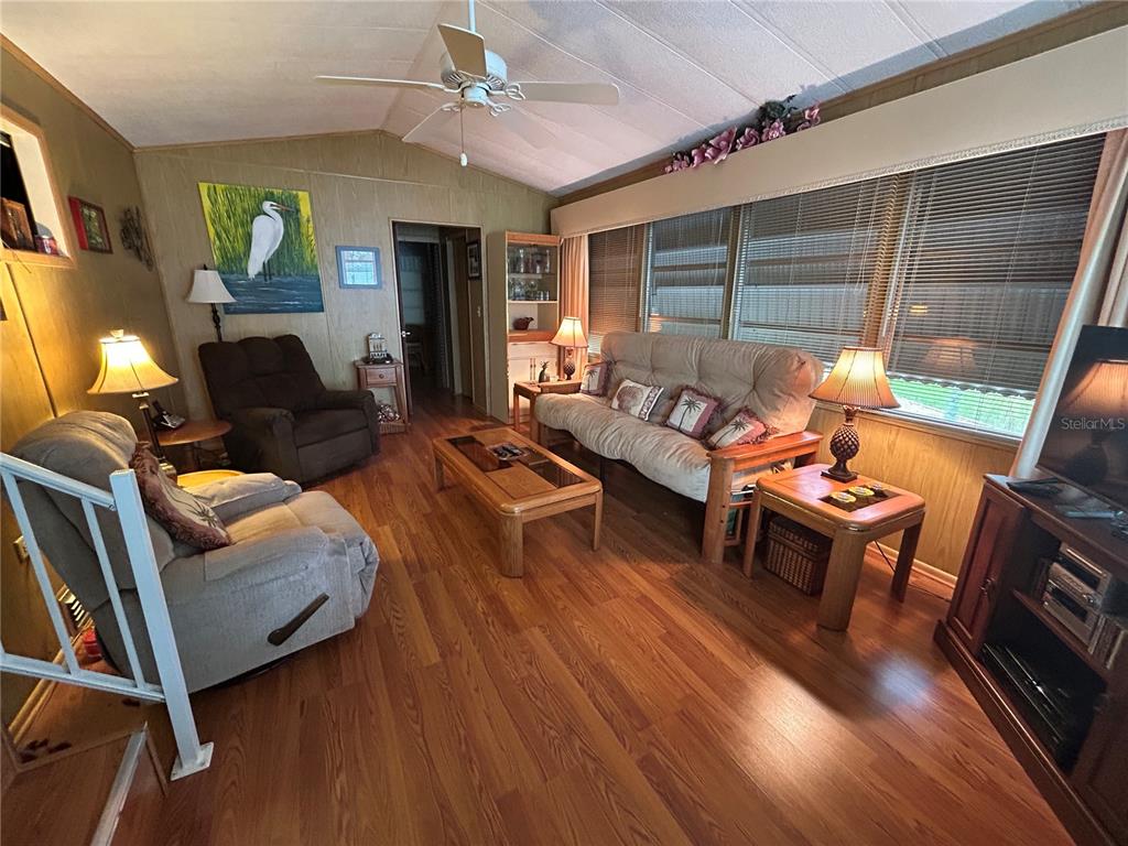 A living room features wood-look flooring, a ceiling fan, a sofa, and two armchairs — 2 WOODRUFF WAY, LAKE WALES, FL