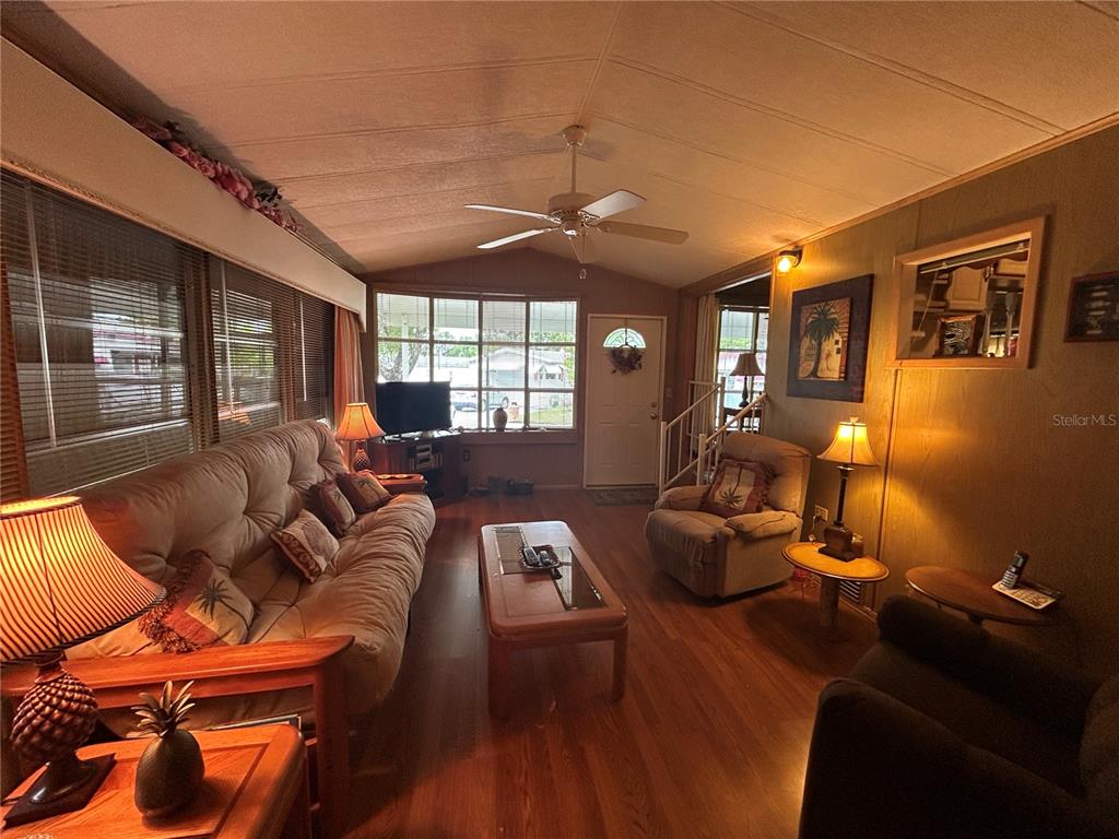 A living room features wood-look flooring, a ceiling fan, a sofa, and a recliner — 2 WOODRUFF WAY, LAKE WALES, FL