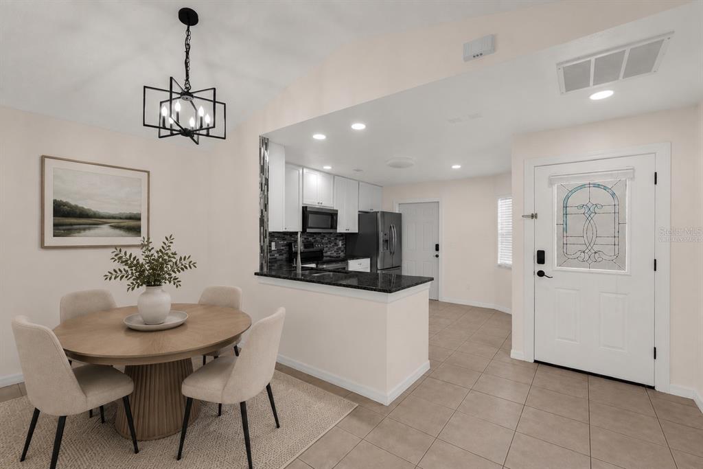 A dining area with a round table sits adjacent to a kitchen with granite countertops — 1455 ELDRA DRIVE, KISSIMMEE, FL