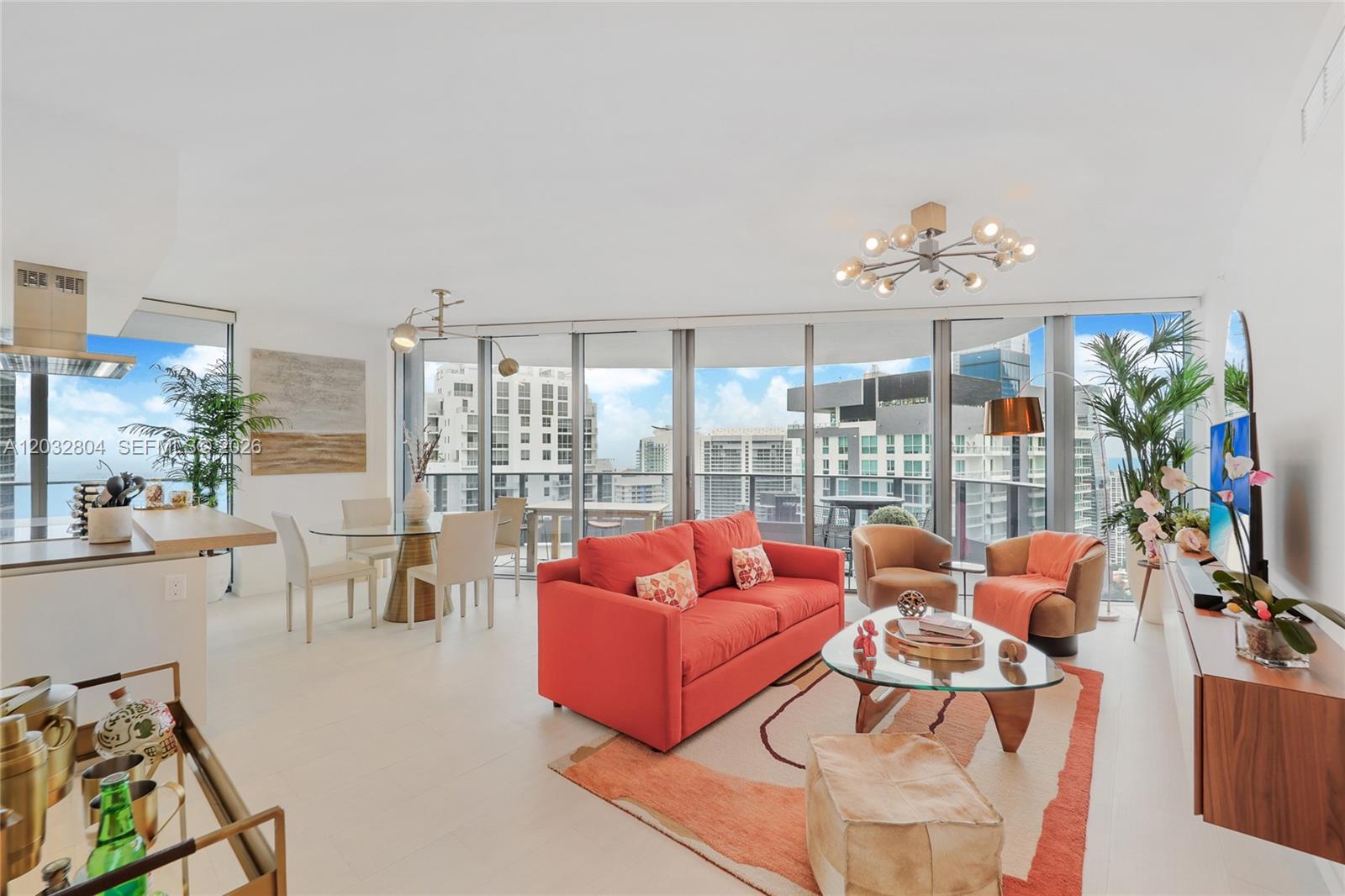 A modern living and dining area features a red sofa, glass tables, and floor-to-ceiling windows — 1000 Brickell Plz # 4401, Miami FL 33131, MIAMI, FL