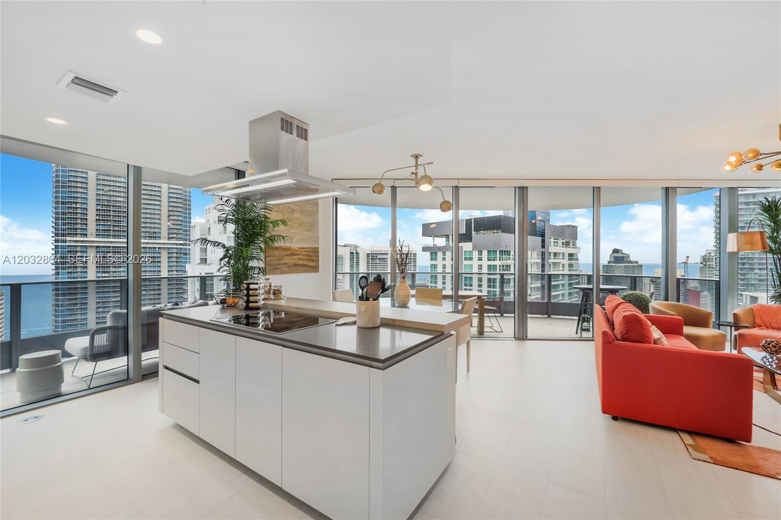 A modern kitchen island with a cooktop sits in an open-concept living space with balconies — 1000 Brickell Plz # 4401, Miami FL 33131, MIAMI, FL