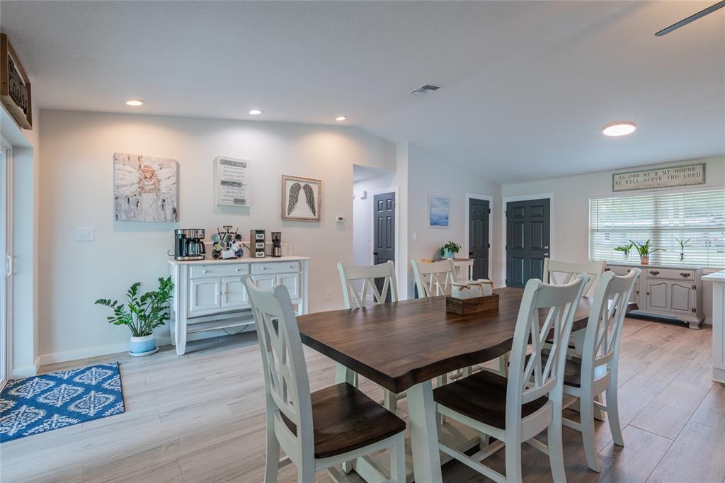 A dining room features a wooden table, white chairs, light flooring, and a coffee station — 19823 ALABAMA ROAD, SPRING HILL, FL