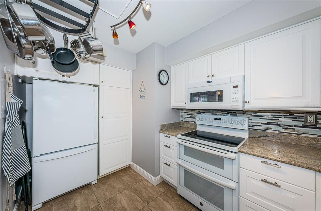 A kitchen features white cabinets, a double oven, a microwave, and a hanging pot rack — 6295 BAHIA DEL MAR CIRCLE UNIT 405, ST PETERSBURG, FL