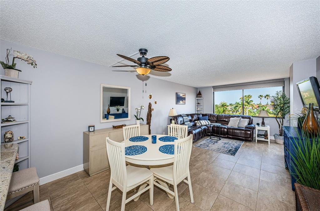 A dining area and living room with tile floors, a ceiling fan, and large windows — 6295 BAHIA DEL MAR CIRCLE UNIT 405, ST PETERSBURG, FL