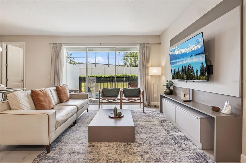 A living room features a beige sofa, a coffee table, and a wall-mounted television — 7952 FORMOSA VALLEY PLACE, KISSIMMEE, FL