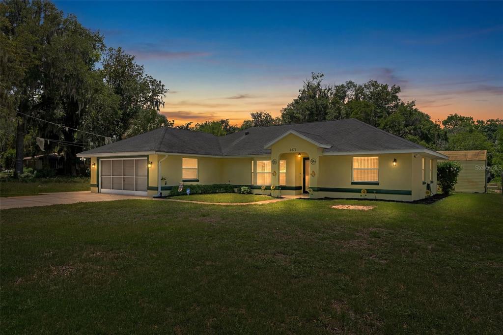 A yellow single-story house with a garage and a large front lawn at dusk — 2472 CR 447, LAKE PANASOFFKEE, FL