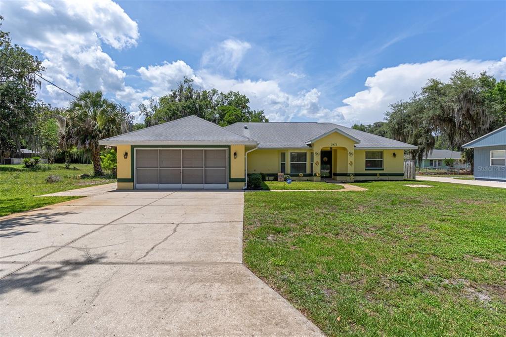 A yellow single-story house with a two-car garage and a concrete driveway — 2472 CR 447, LAKE PANASOFFKEE, FL