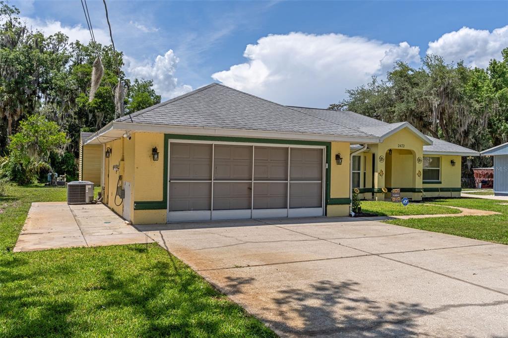 A yellow house with a large garage, concrete driveway, and a covered front entrance — 2472 CR 447, LAKE PANASOFFKEE, FL