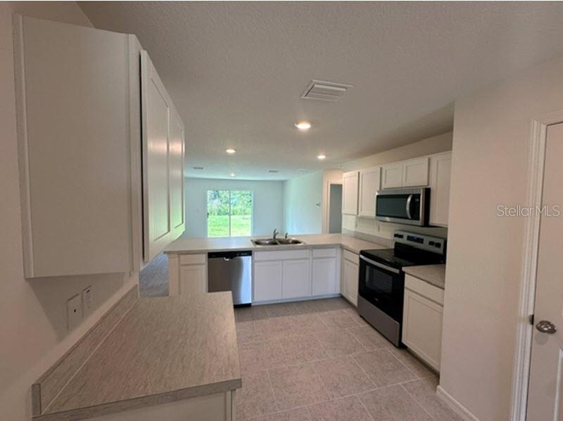 A kitchen with white cabinets, stainless steel appliances, and light-colored tile flooring — 91 RANDOLPH DRIVE, PALM COAST, FL