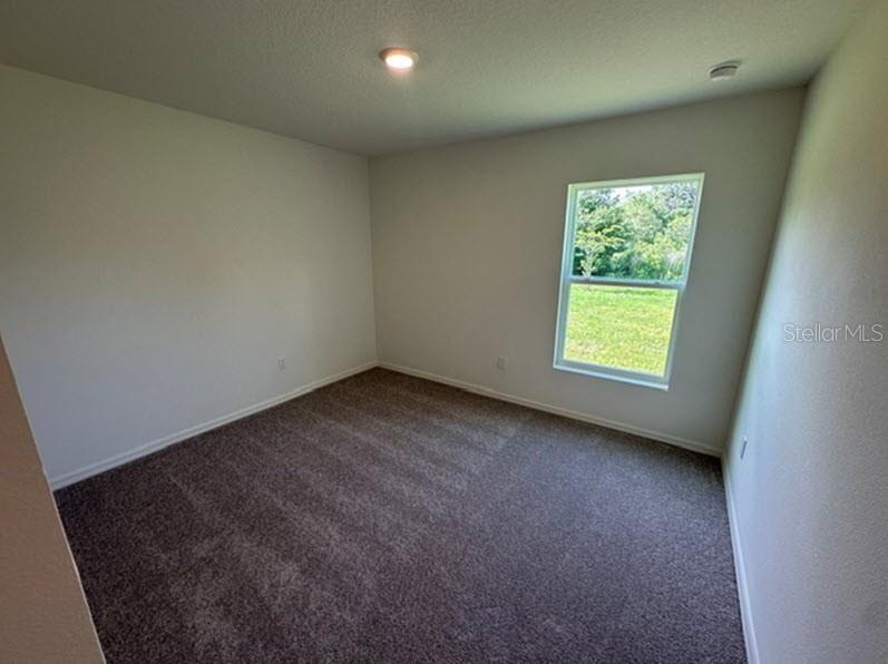 An empty bedroom features neutral walls, dark carpeting, a single window, and a ceiling light — 91 RANDOLPH DRIVE, PALM COAST, FL