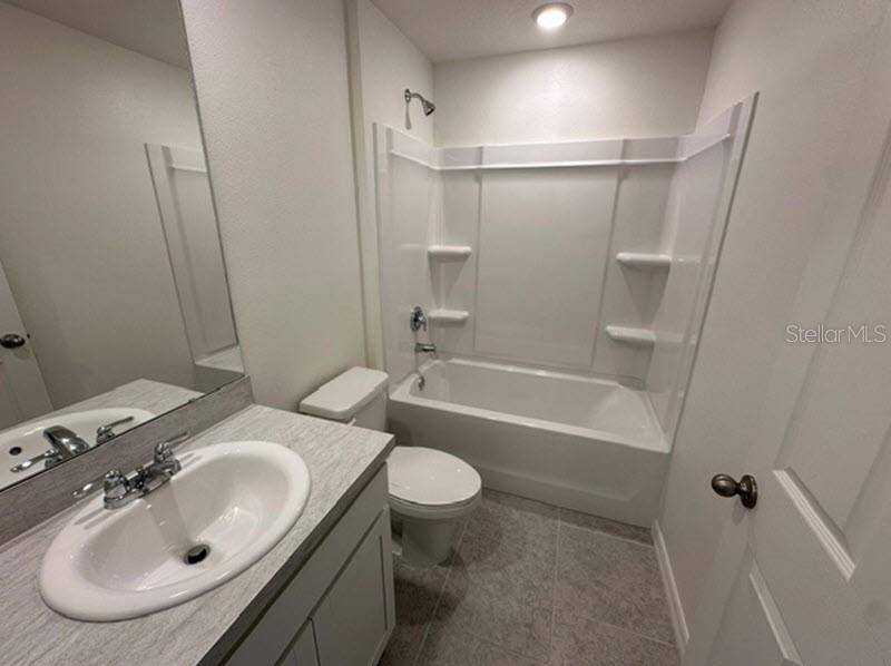 A bathroom with a white vanity, a toilet, and a shower-tub combination with white walls — 91 RANDOLPH DRIVE, PALM COAST, FL