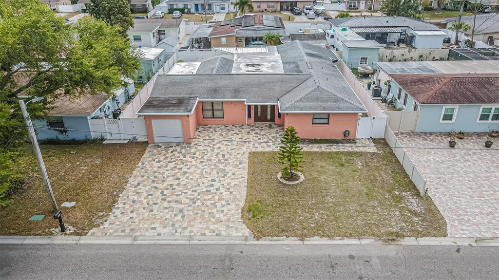 An aerial view shows a pink, single-story house with a paved driveway and front yard — 3112 W HENRY AVENUE, TAMPA, FL