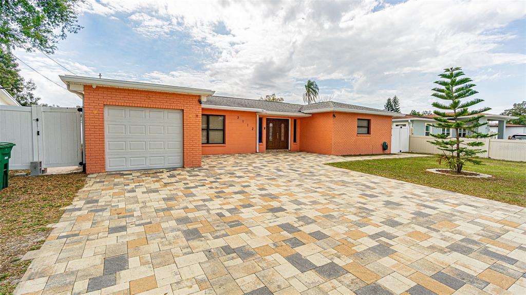 A single-story orange brick house features a paved driveway, a garage, and a front entrance — 3112 W HENRY AVENUE, TAMPA, FL