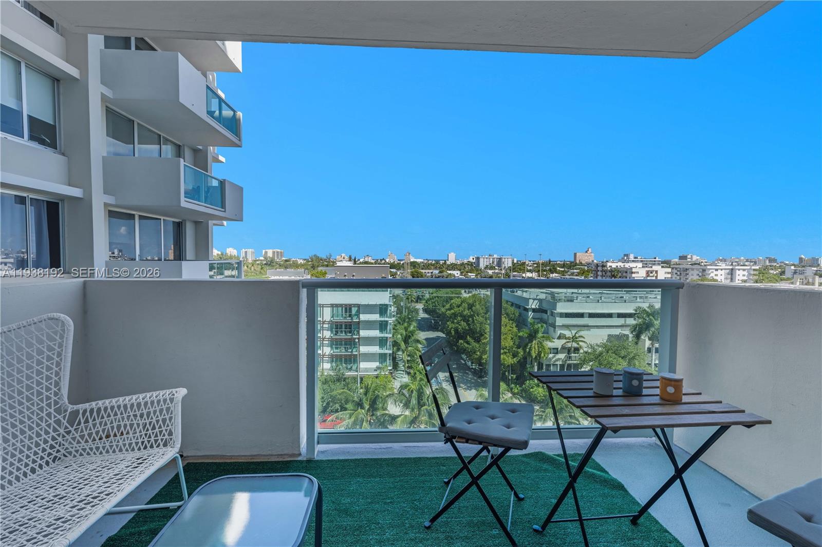 A balcony features a small table, two chairs, and a view of surrounding buildings — 1200 West Ave # 811, Miami Beach FL 33139, MIAMI BEACH, FL