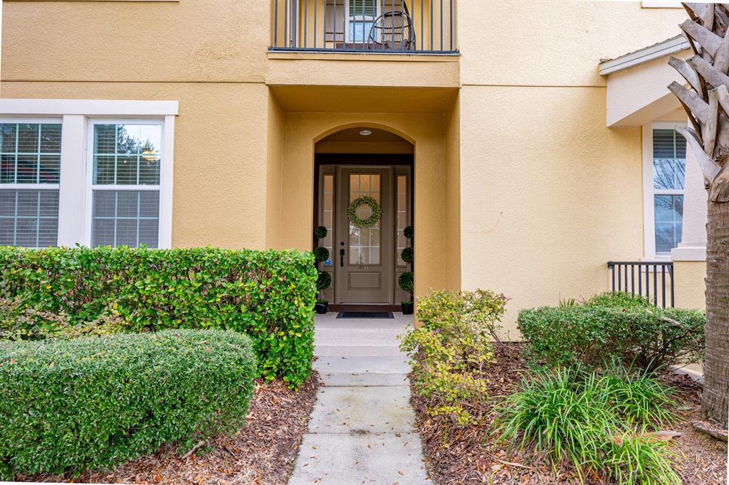 The exterior of a tan stucco building features a front entryway with a glass door — 12305 VIA DERNA PLACE, WINDERMERE, FL