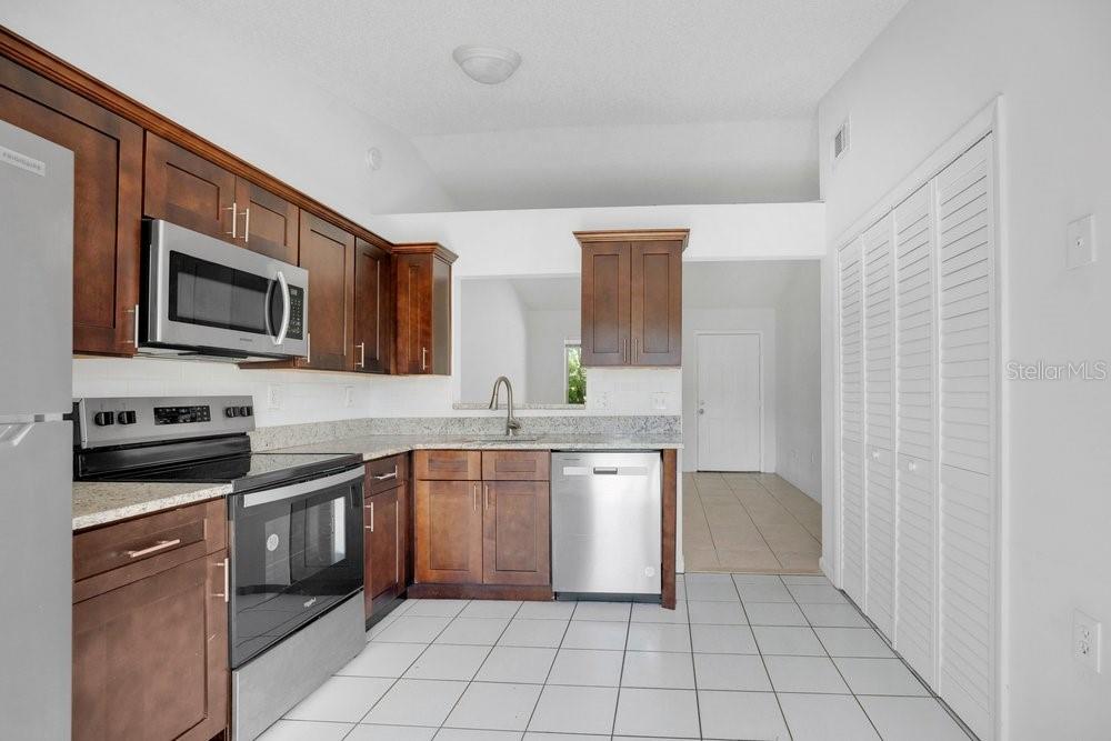 A kitchen with dark wood cabinets, stainless steel appliances, and white tile flooring — 2827 CORAL REEF DRIVE, ORLANDO, FL