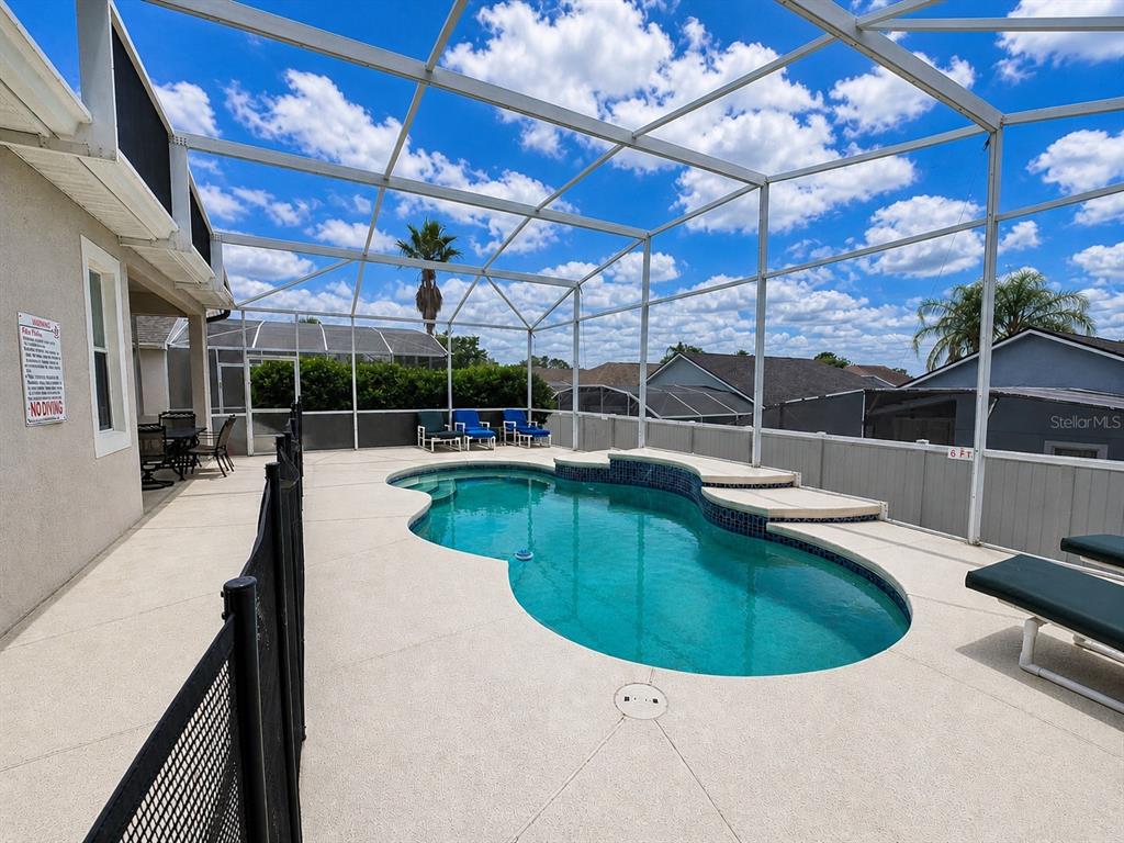 A screened-in swimming pool with a patio and lounge chairs under a blue sky — 205 GLENEAGLES DRIVE, DAVENPORT, FL