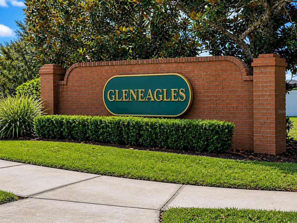 A brick entrance sign for Gleneagles stands behind a manicured hedge and green lawn — 205 GLENEAGLES DRIVE, DAVENPORT, FL