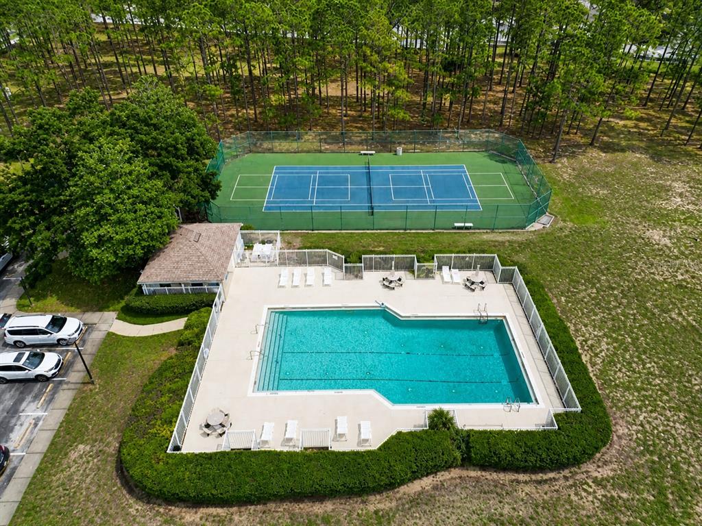 An aerial view shows a swimming pool and a tennis court surrounded by trees — 205 GLENEAGLES DRIVE, DAVENPORT, FL