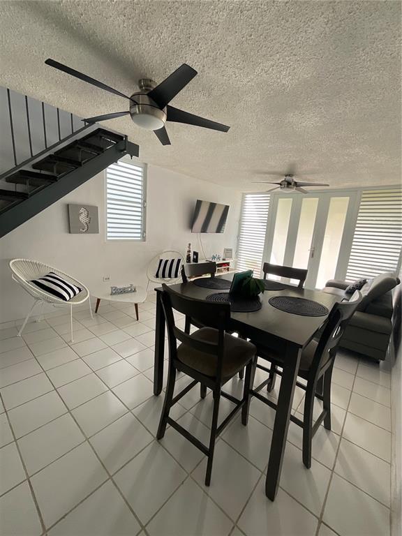 A dining area with a dark table and chairs sits near a staircase and living space — Villa Marina Village APT 5 B, FAJARDO, PR