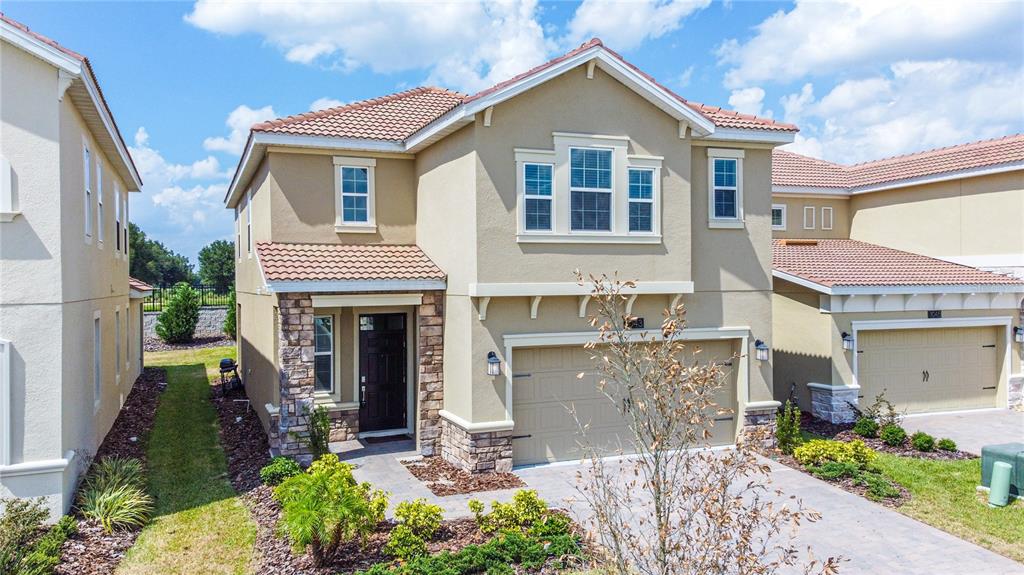 A two-story house with a tan stucco exterior, stone accents, and a tiled roof — 1043 BLACKWOLF RUN ROAD, DAVENPORT, FL