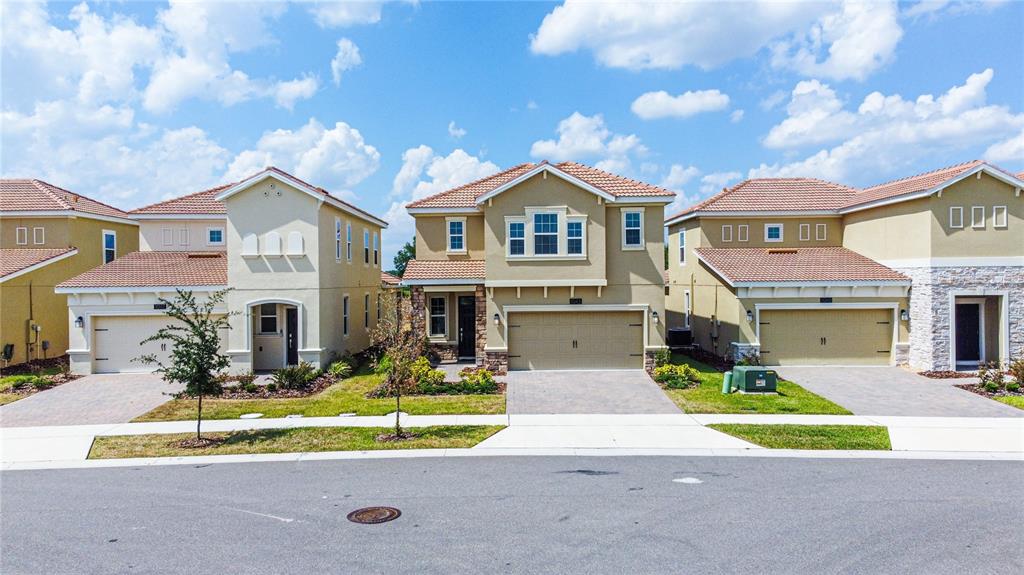 Three suburban houses with tiled roofs and paved driveways stand along a residential street — 1043 BLACKWOLF RUN ROAD, DAVENPORT, FL