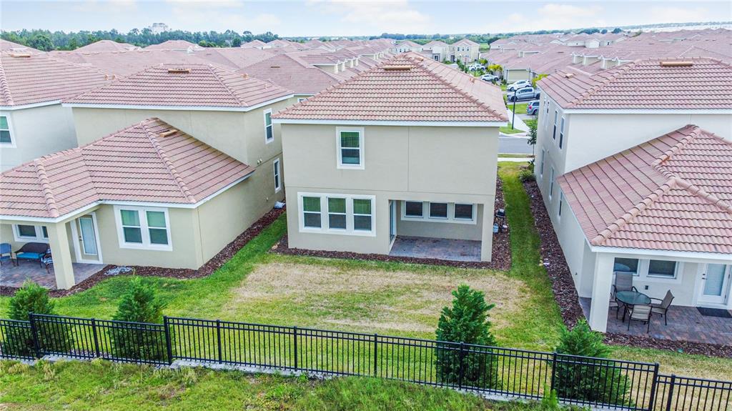 An aerial view shows the back of a two-story house with a fenced backyard — 1043 BLACKWOLF RUN ROAD, DAVENPORT, FL