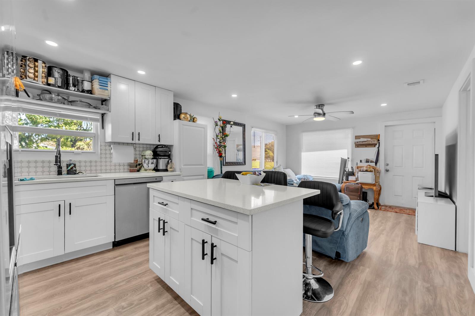 A white kitchen with an island, stainless steel appliances, and wood-look flooring — 621 NW 15th Avenue, Pompano Beach FL 33069, POMPANO BEACH, FL
