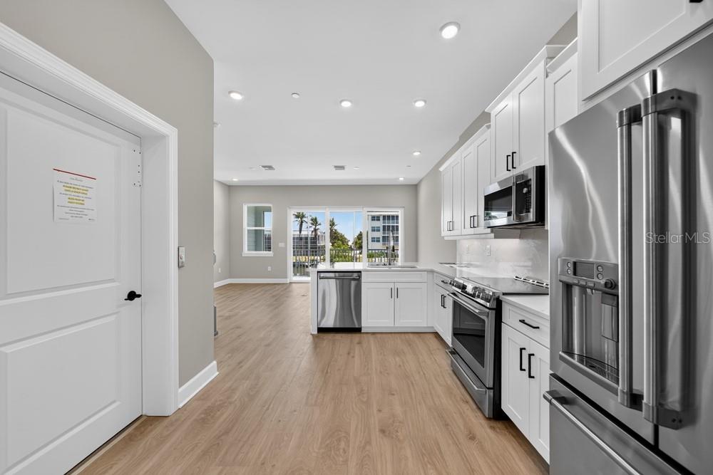 A kitchen with white cabinets and stainless steel appliances opens to a living area — 1617 SEA HAVEN DRIVE UNIT 504, PUNTA GORDA, FL