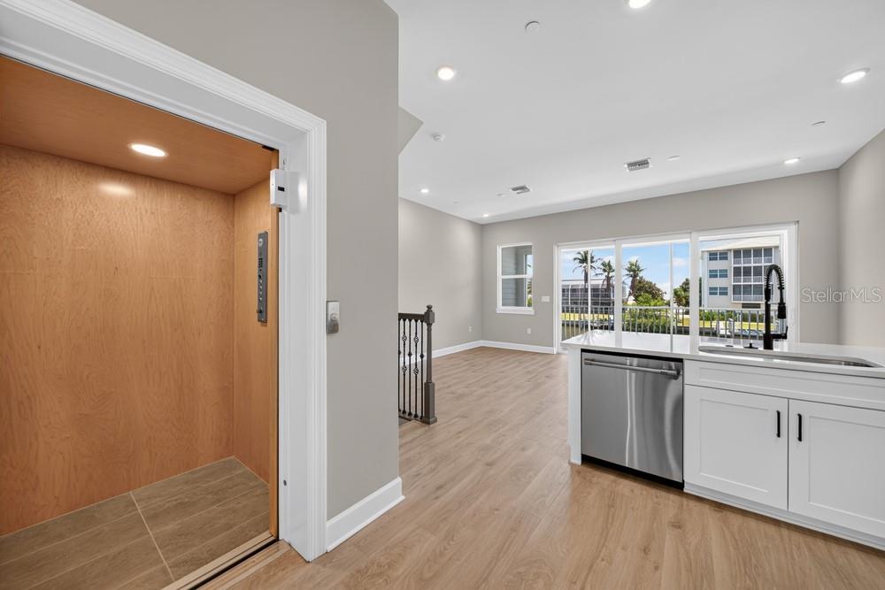 A kitchen with white cabinets and a dishwasher sits next to an indoor home elevator — 1617 SEA HAVEN DRIVE UNIT 504, PUNTA GORDA, FL