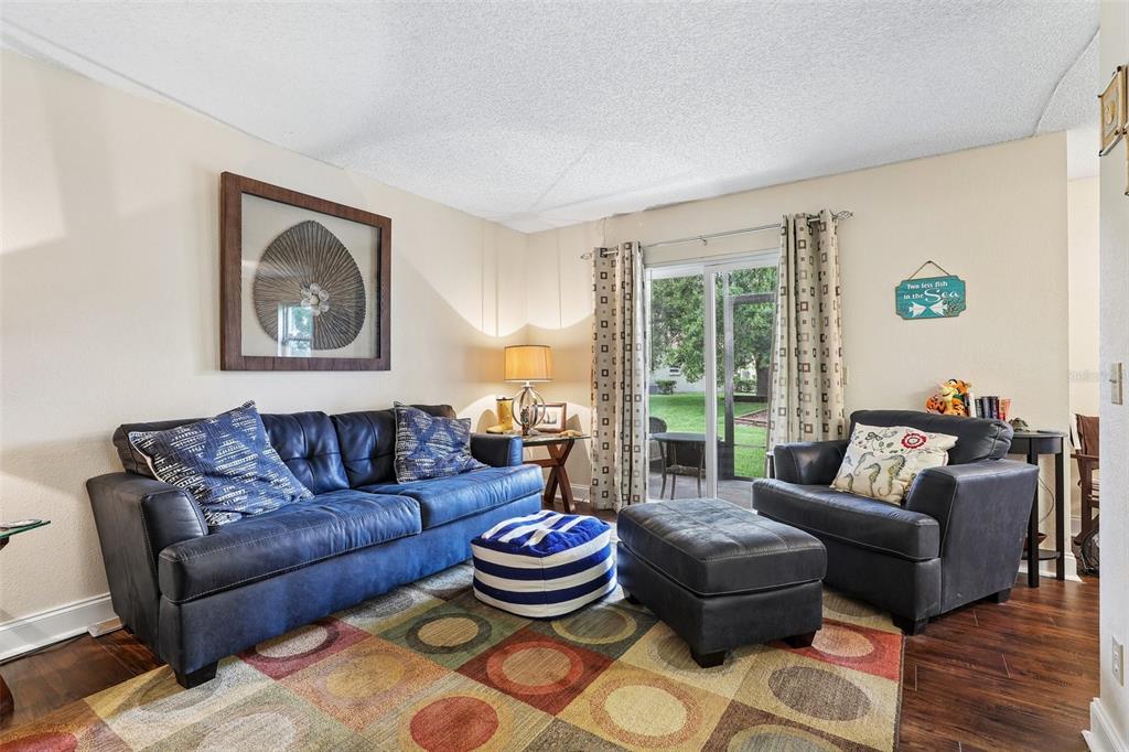 A living room features a blue sofa, matching armchair, ottoman, and a colorful patterned rug — 9902 TURF WAY UNIT 6, ORLANDO, FL