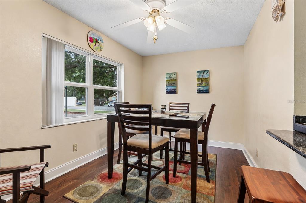 A dining room with a dark wood table, four chairs, a colorful rug, and a window — 9902 TURF WAY UNIT 6, ORLANDO, FL