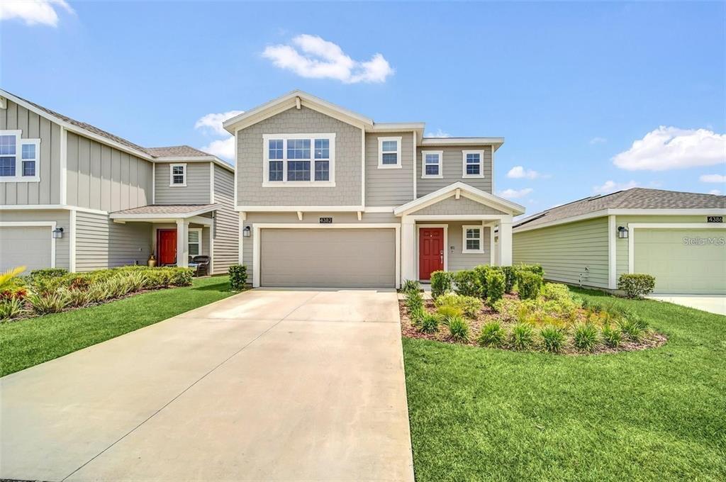 A two-story suburban house with gray siding, a red front door, and a concrete driveway — 4382 SUNNY CREEK PL, KISSIMMEE, FL