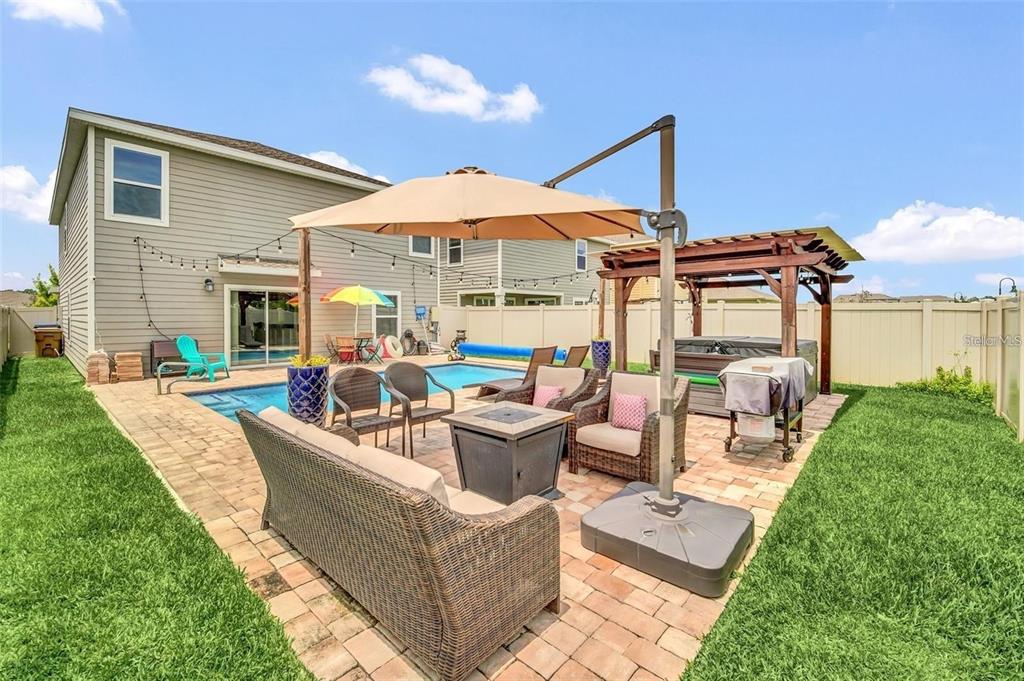 A backyard patio features a swimming pool, fire pit, outdoor furniture, and a wooden pergola — 4382 SUNNY CREEK PL, KISSIMMEE, FL