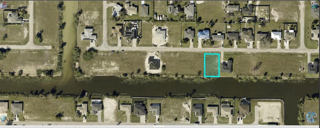 An aerial view shows a vacant rectangular waterfront lot highlighted in blue within a residential neighborhood — 934 NE 12TH STREET, CAPE CORAL, FL